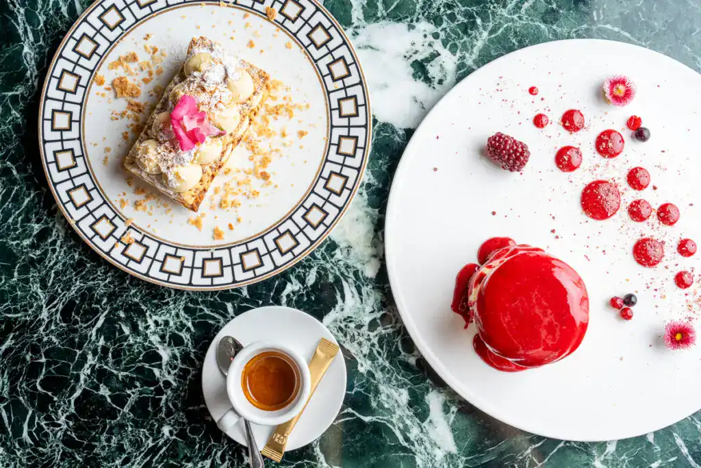 Wunderschöner Kuchenteller mit detailreicher Desserts auf grünem Marmor-Tisch, perfekt für hochwertige Kaffee- und Konditoreikreationen.