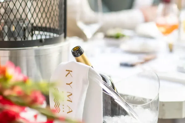 817A6583-Verbessert-RR Kymata Modern, elegante Flasche mit Sekt in Eiskübel bei einem festlichen Event, stilvolles Ambiente, moderne Tischdekoration, hochwertige Eventplanung, exklusiv.